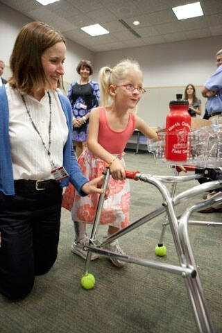 GVSU Engineer helping a child with a device designed for her.